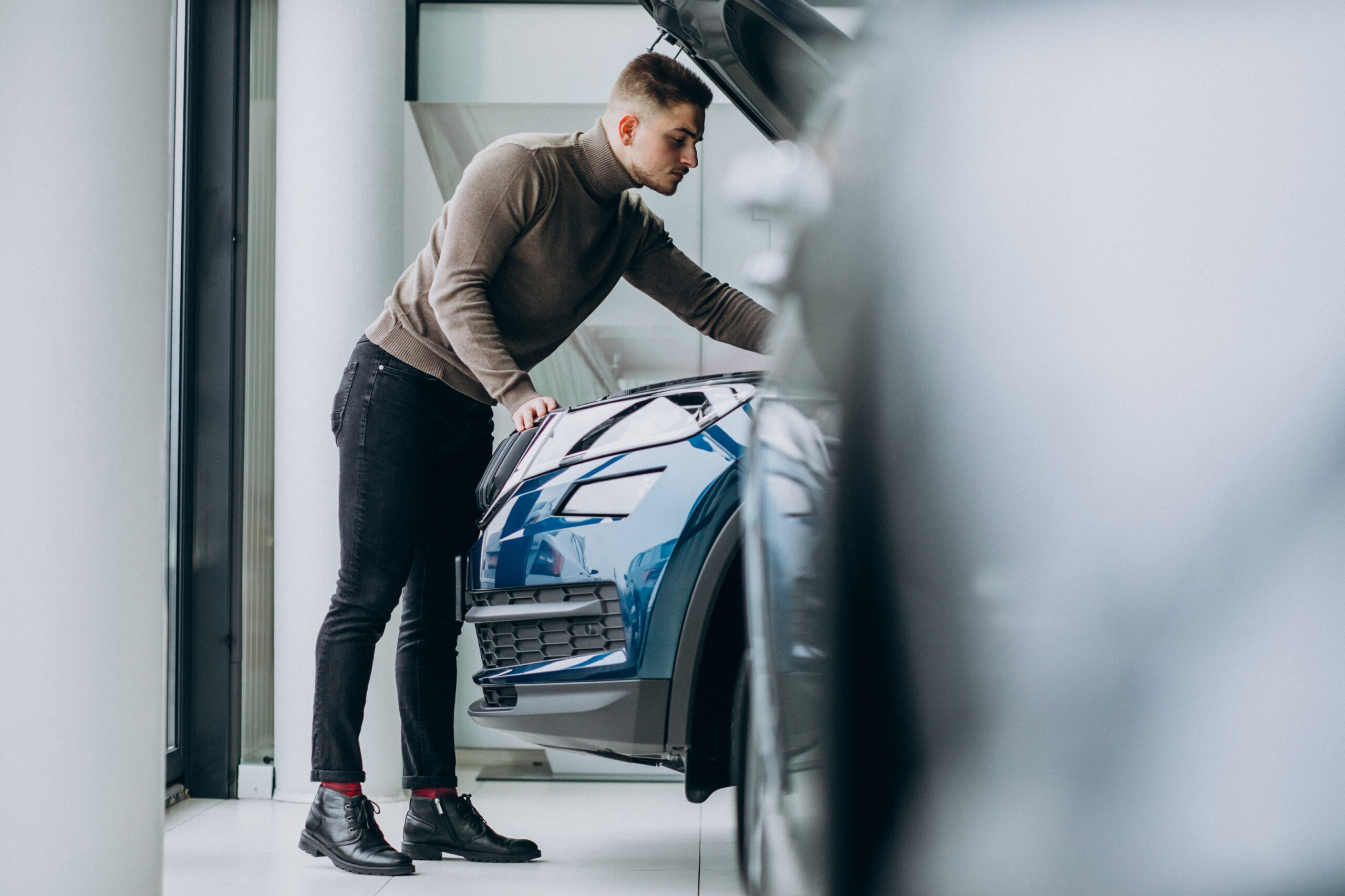 Young handsome man choosing a car in a car showroom - Supercarvault | Secure Storage for Supercars & Classic Cars
